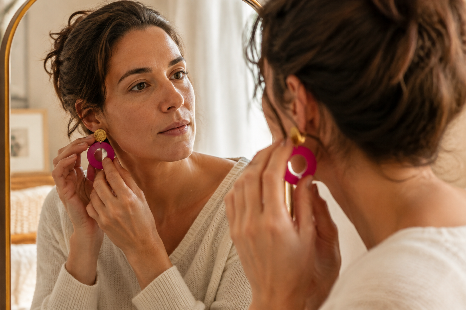 Femme choisissant ses boucles d’oreilles LIBRES. devant un miroir