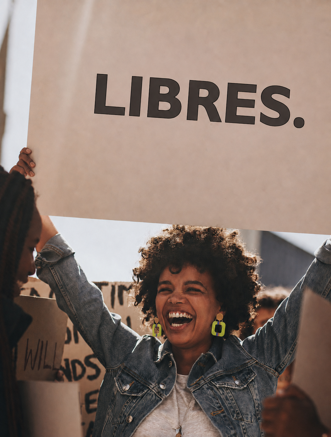 Femme portant des boucles d’oreilles colorées LIBRES. et une pancarte LIBRES.